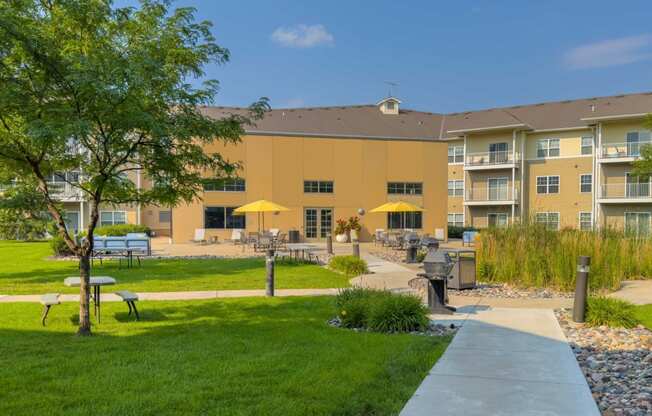 a large apartment building with a lawn and picnic tables