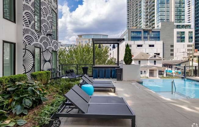 the pool and lounge area of an apartment building with a pool and skyscrapers