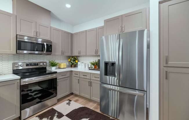 a kitchen with stainless steel appliances and white cabinets at Weylyn Luxury Apartments, Laveen, 85339