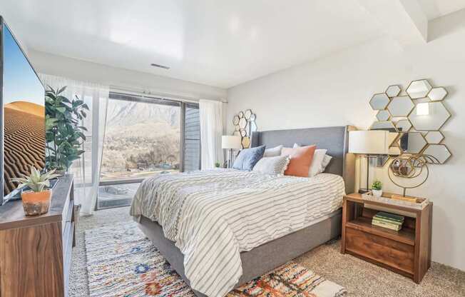 A bedroom with a large bed and a view of the mountains outside the window.