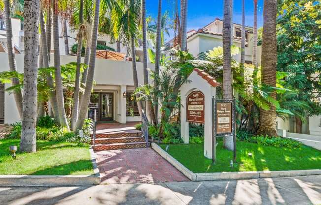 a house with palm trees and a sign in front of it