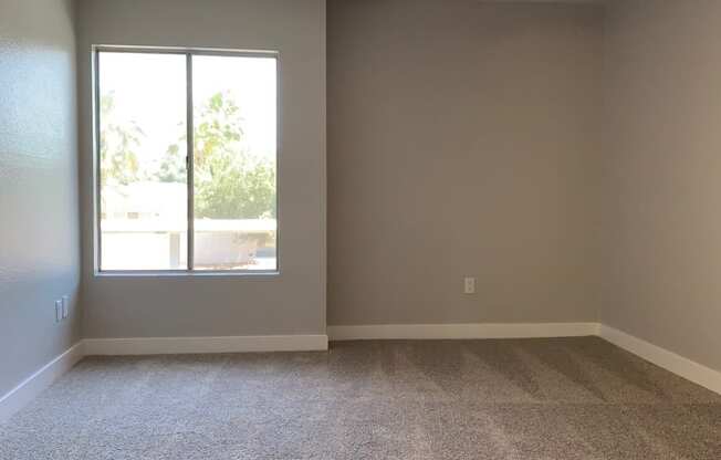 an empty living room with a ceiling fan and a window