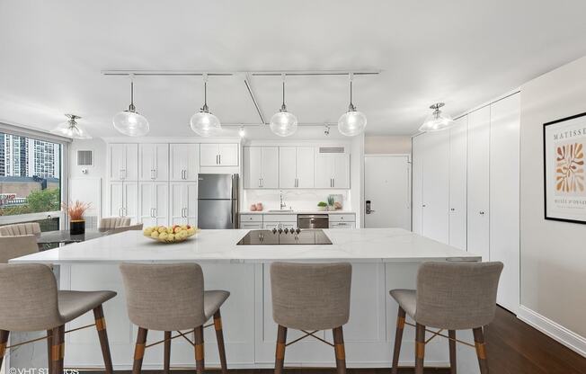 a kitchen with white cabinets and a white counter top and chairs