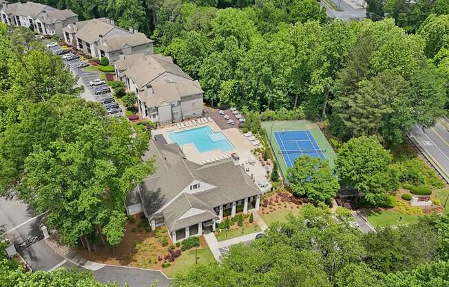 A bird's eye view of a residential are with a swimming pool and tennis court.