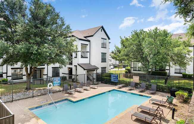Smaller community pool with lounge chairs, fenced deck, and surrounding apartment buildings.