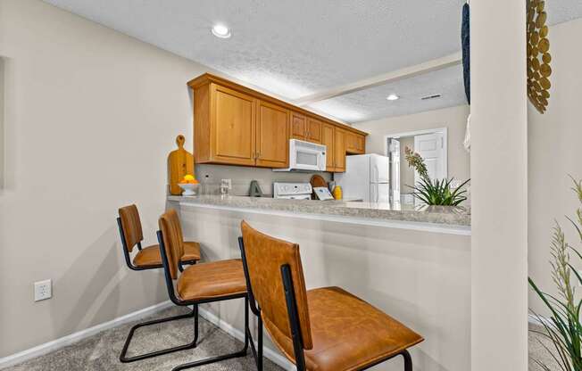 A kitchen with brown chairs and white walls.