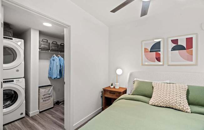 A bedroom with a green bed and a washing machine in the closet.
