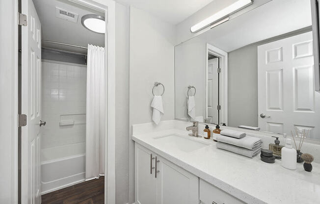 Model Bathroom with White Cabinets, Wood-Style Flooring and Shower/Tub at Crystal Creek Apartments located in Phoenix, AZ.