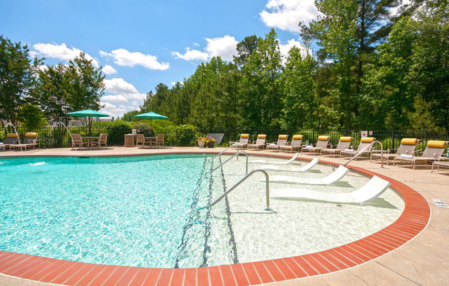 a swimming pool with chairs and umbrellas at Millennium Apartments Greenville SC
