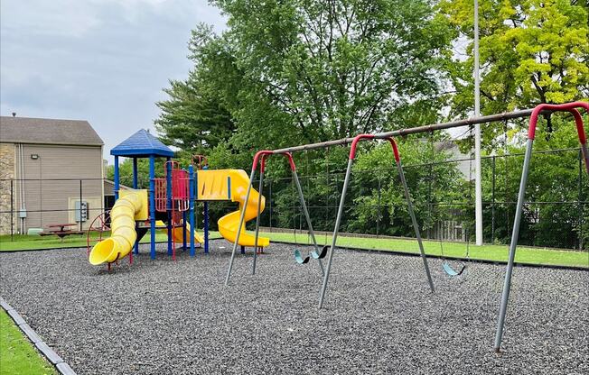 A playground with a yellow slide and a blue canopy.