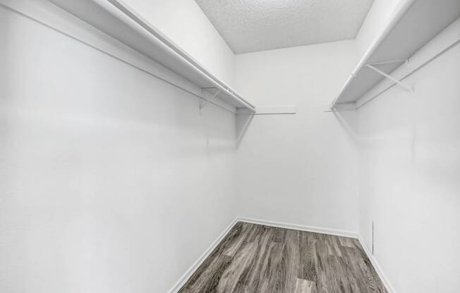 an empty room with white walls and wood flooring and a white closet