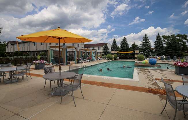 a swimming pool with tables and umbrellas and people in it at Village Club of Rochester Hills, Shelby Township, MI 48317