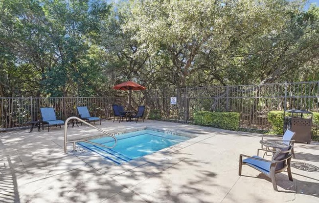 a pool with chairs and an umbrella in a backyard with trees