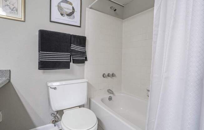 A white toilet sits next to a bathtub in a cypress bathroom at The Marq in Shreveport, LA