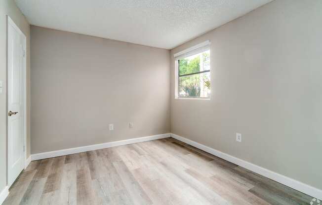 an empty room with wood floors and a window