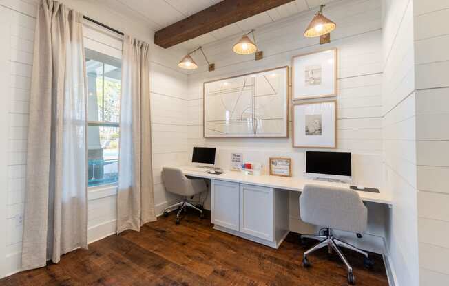 a home office with white shiplap walls and a desk with two computers