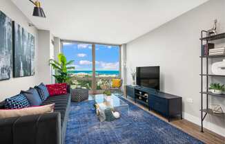 a living room with a couch and a tv and a view of the ocean