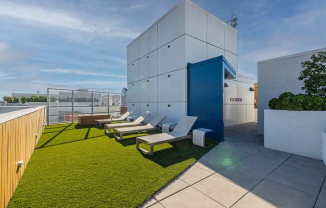 a rooftop terrace with lounge chairs and a building in the background