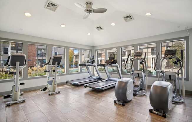 A gym with treadmills, elliptical machines, and a fan.