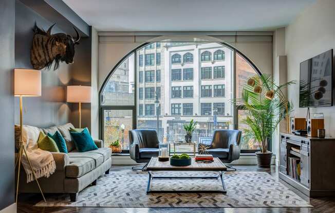 a living room with a large arched window and a couch and chairs