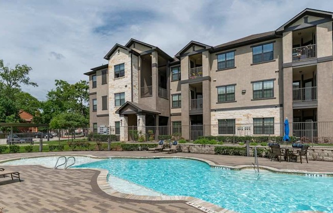 A large swimming pool is located in front of apartment buildings.
