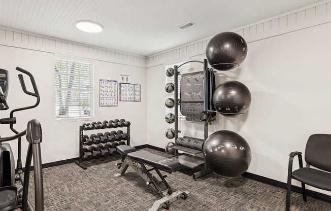 A gym room with a variety of equipment including a treadmill, weights, and a bench.