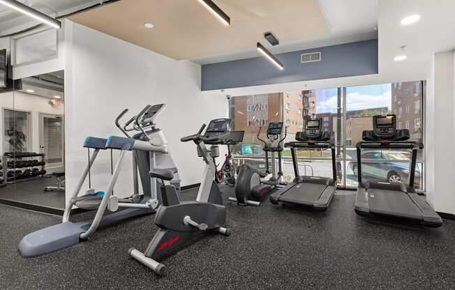 a gym with treadmills and other exercise equipment in a room with a window