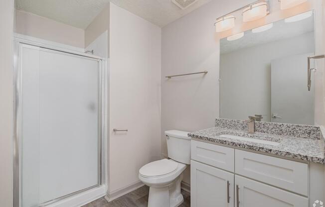 A white bathroom with a toilet, sink, and shower.