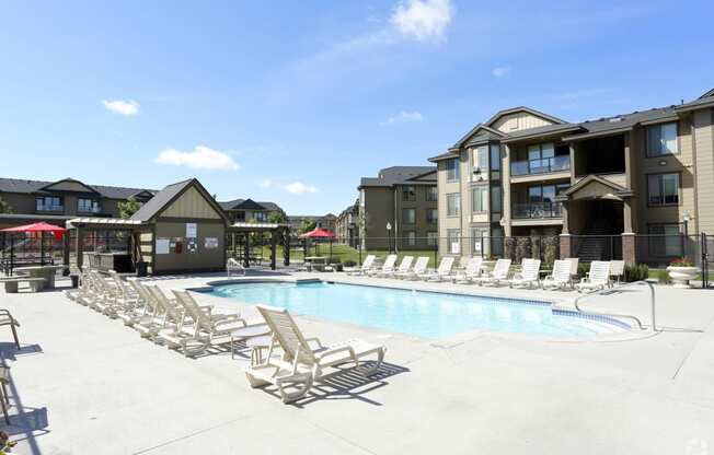 A swimming pool with chaise lounge chairs and a building in the background