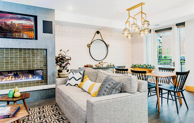 Cozy communal lounge in the apartment complex featuring stylish seating arrangements, a modern flat-screen TV, a warm fireplace, and a tabletop shuffleboard for residents to enjoy.