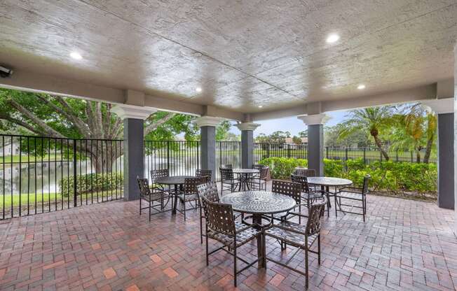 a covered patio with tables and chairs and a fence