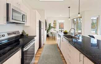 A modern kitchen with black countertops and white cabinets.