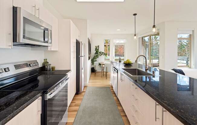 A modern kitchen with black countertops and white cabinets.