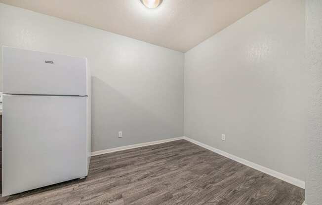 a bedroom with a refrigerator and hardwood floors