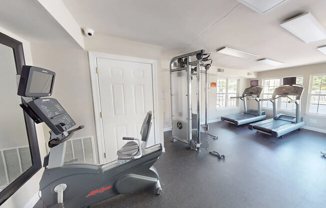 A home gym with a treadmill, elliptical machines, and other exercise equipment.