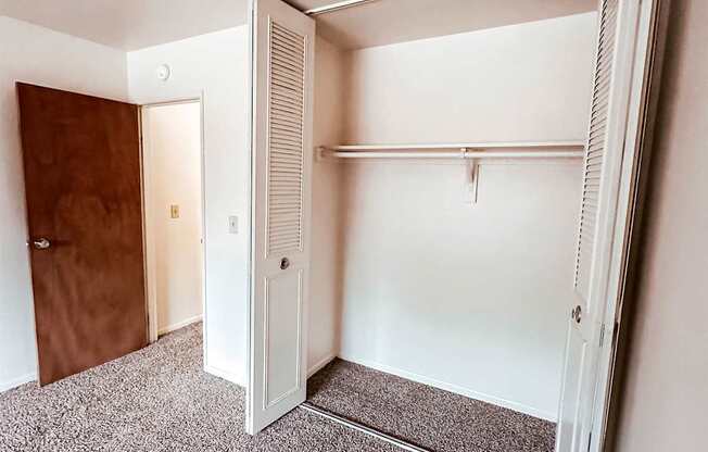 A white closet with a brown door is open.