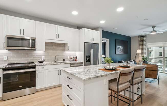 a kitchen with white cabinets and a marble counter top