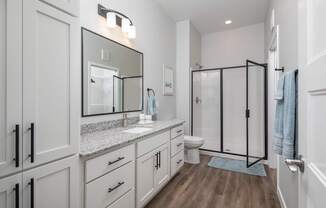 A bathroom with a toilet, sink, and mirror.