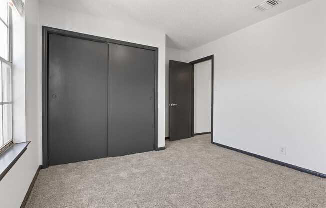 the living room of an apartment with two closets and two doors