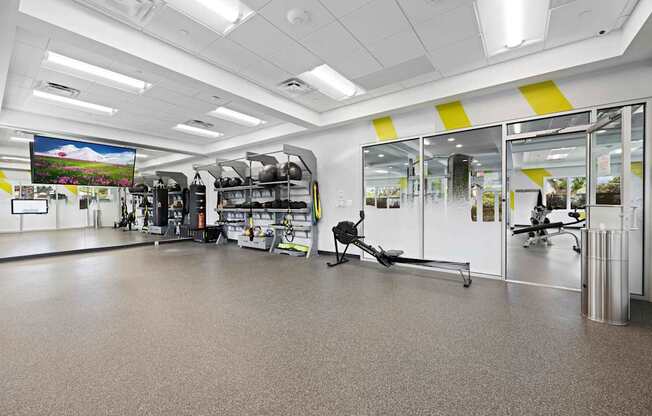 A gym with a variety of equipment including treadmills, weights, and exercise machines.