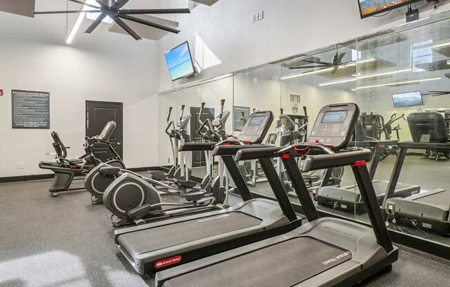 A gym with treadmills, elliptical machines and other exercise equipment.
