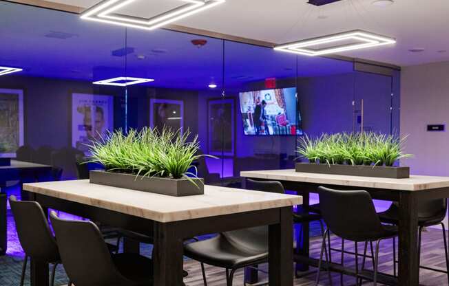 a room with tables and chairs and a tv in the background