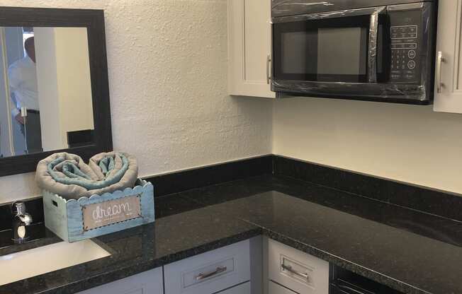 a kitchen with white cabinets and black countertops at Colonial Apartments, Orlando Florida