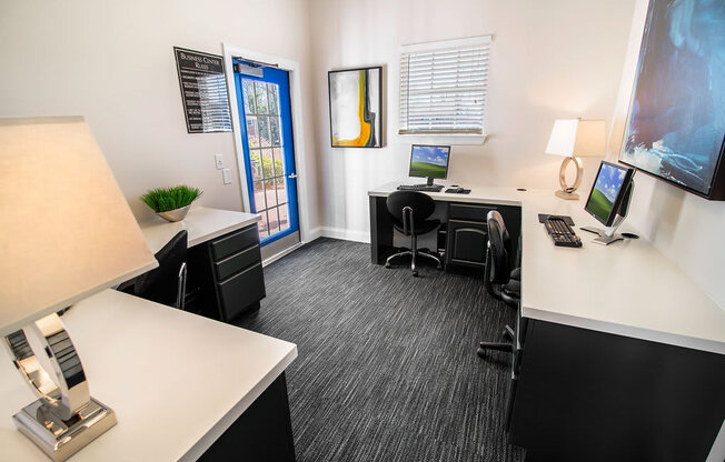 A modern office with a white desk, black chairs, and a computer setup.