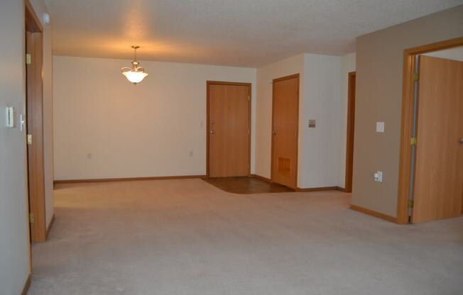 an empty living room with three doors and a lamp