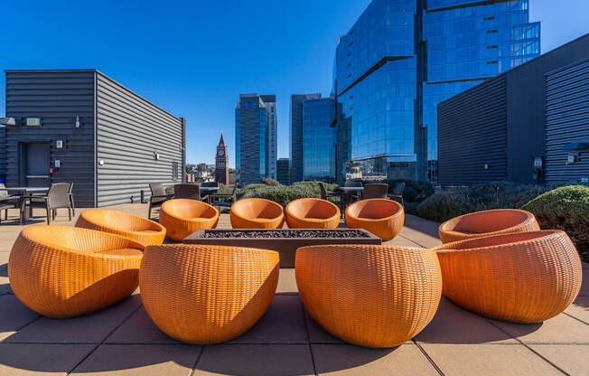 a lounge area with orange chairs and a table in front of tall buildings
