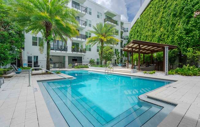 A swimming pool surrounded by a white building and palm trees.