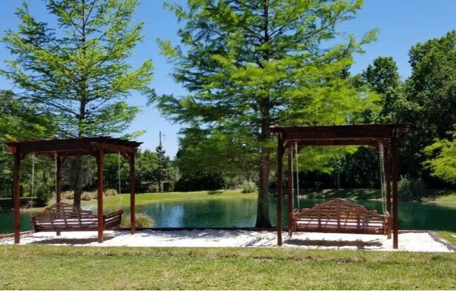 2 Pergola swing beds located on top of sand box located near the pond.