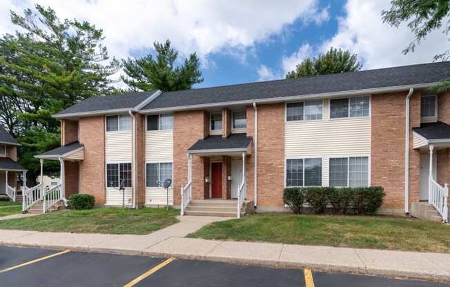 an apartment building with brick and white siding and a lawn