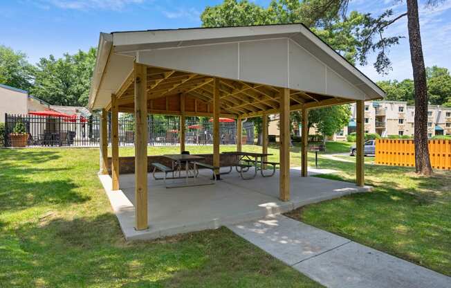 a picnic pavilion with benches and tables in a park